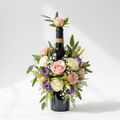 Wine bottle decorated with fresh flowers and greenery as a floral gift