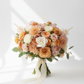 A lush mid-sized fresh flower bouquet with warm pinks, peaches, and creams